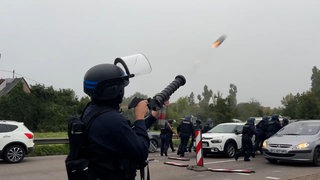 Ein Polizist schließt eine Tränengaspatrone in Richtung von Demonstrierenden