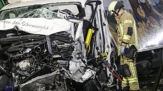 Ein Feuerwehrmann steht neben einem völlig demoliertem Transporter. 