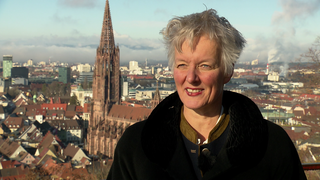 Frau steht vor Münster-Kulisse in Freiburg.