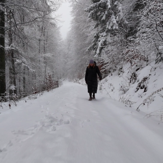 Eine Frau läuft durch den Schnee im Wald