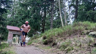 Ultraläufer Daniel Hernes läuft durch ein Westweg-Portal.