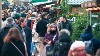 Besucher laufen über den Weihnachtsmarkt in Straßburg.
