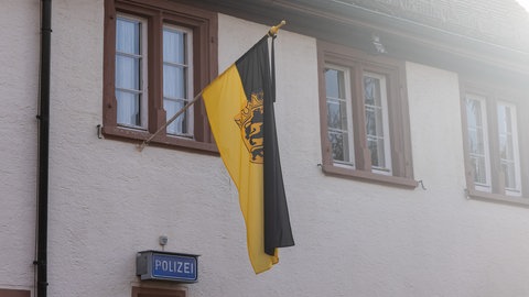 Die baden-württembergische Landesfahne hängt gemeinsam mit einem Trauerflor am Polizeirevier in Titisee-Neustadt