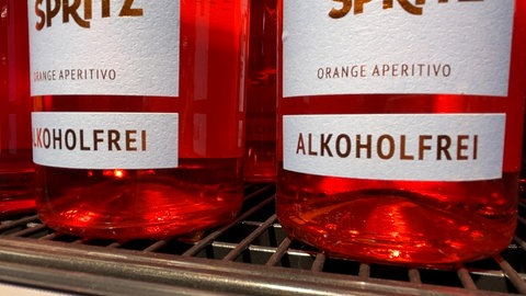 Zwei Flaschen mit alkoholfreiem Schaumwein stehen in einem Regal.