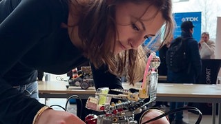 Eine Studentin schaltet ihren selbstgebauten Roboter ein