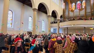 Papierflieger fliegen während der Narrenmesse durch die Stadtkirche St. Bonifatius in Lörrach. 