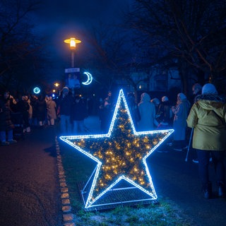 Menschen stehen um eine sternförmige Lichtinstallation der Ramadan-Festbeleuchtung in Freiburg.