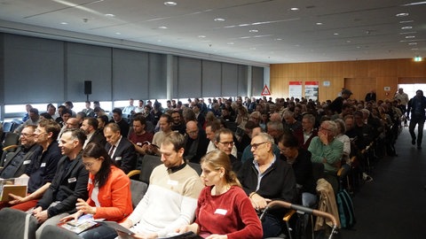 300 Menschen sitzen vor einer Bühe.