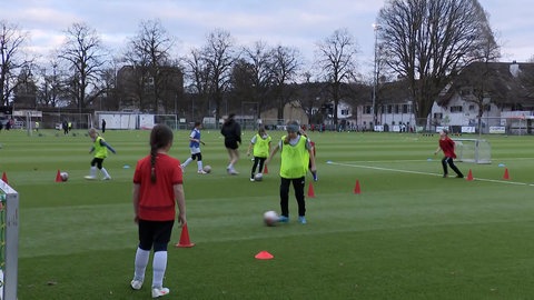 Fußballspielerinnen trainieren auf dem Platz in bunten Leibchen