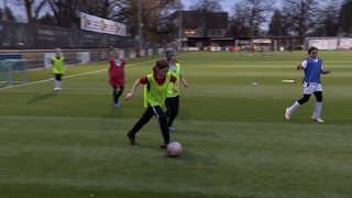 Fußballspielerinnen trainieren auf dem Platz in bunten Leibchen