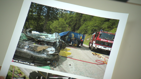 Ein umgekippter LKW liegt mitten auf der Straße, daneben ein zerbeultes Auto.