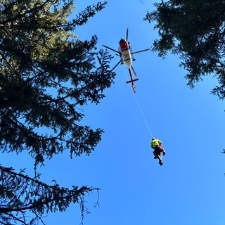 Rettungskräfte von DRF Luftrettung und Bergwacht werden in den Rettungshubschrauber gezogen.