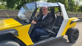 Chistophe Winkelmuller, Gründer von IPOP Automobiles, sitzt in einem Elektroauto, das an ein Golfcart erinnert.