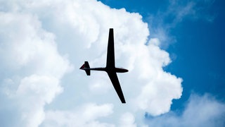 Ein Segelflugzeug fliegt unter einer Wolke. (Symbolbild)