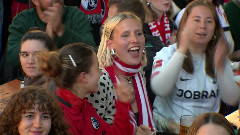 Weibliche Fans des SC Freiburg sitzen in einem Freiburger Biergarten und feuern ihr Team an. 