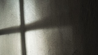 Ein Fenster wirft ein Schatten in Form eines Kreuzes an die Wand. In Bernau kämpft eine Gemeinde damit, dass ihr Pfarrer Kinder missbraucht hat