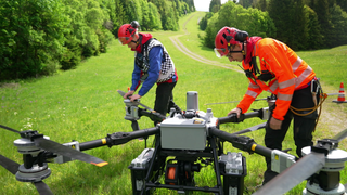 Zwei Bergretter üben den Einsatz einer neuen 3 mal 3 Meter großen Lastendrohne im Schwarzwald.