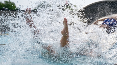 Die Beine eines Kindes ragen aus dem Wasser. Es ist wohl ins Schwimmbecken gerutscht.