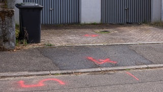Am Tatort sind Spuren gesichert. Rote Markierungen auf dem Gewhweg und in einer Hofeinfahrt.