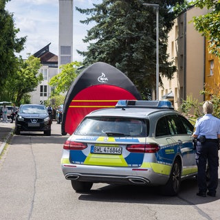 Beamte der Kriminalpolizei und der Kriminaltechnik stehen in einem Offenburger Wohngebiet, während im Vordergrund ein Einsatzfahrzeug der Polizei steht.