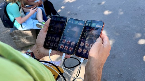 Blick auf den Bildschirm von drei Handys, auf denen das Handyspiel Pokémon GO läuft. Es wird dieses Jahr zehn Jahre alt.