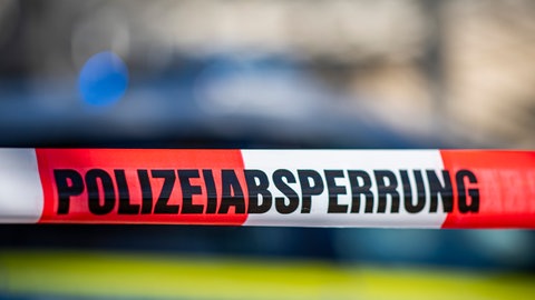 Eine Absperrung der Polizei ist vor einem Polizeiwagen gespannt. 