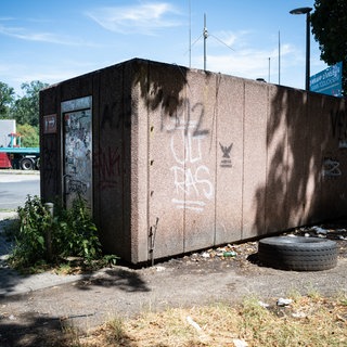 Ein verdrecktes Toilettenhaus an einer Raststätte mit Graffiti und Stickern. 