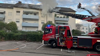 Foto zeigt brennendes Haus und davor ein Feuerwehrauto mit Drehleiter