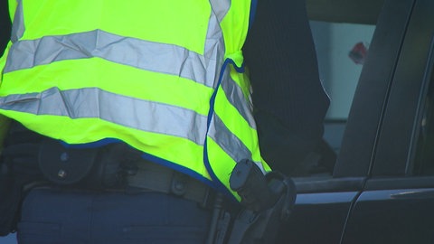 Ein Polizist steht am offenen Fenster eines Autos.