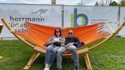 Eine Frau und ein Mann liegen in einer Hängematte.