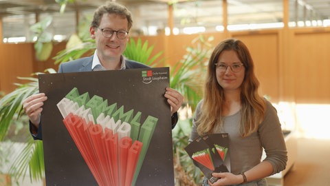 Laupheims Oberbürgermeister Ingo Bergmann hält ein Plakat für die Laemmle Film- und Kinotage. Neben ihm steht Lena Glück.