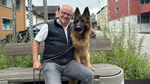 Hündin Ayla und ihr Besitzer sitzen auf einer Bank