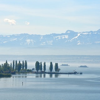 Zwei Fähren fahren bei Meersburg vor dem Panorama der Schweizer Alpen über den Bodensee. 