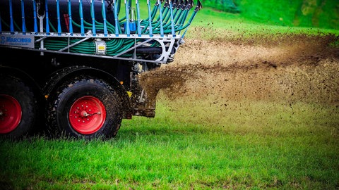 Ein Landwirt bringt mit einem Traktor Gülle aus. 
