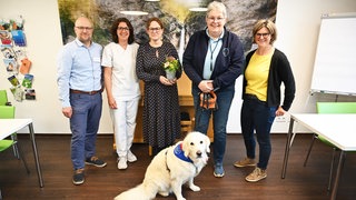 Therapiehündin Emma mit Frauen und Männern in der Klinik