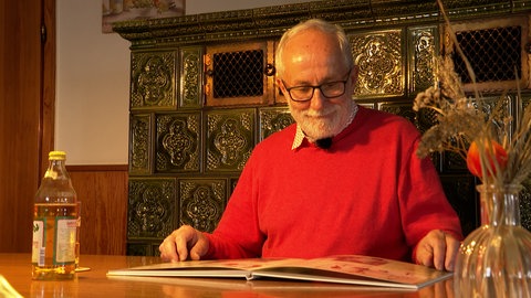 Max Hahn blättert durch ein Fotoalbum, das seine Vorfahren zeigt.