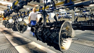 Ein Mitarbeiter von ZF geht im Werk in Friedrichshafen am Bodensee an einem Lkw-Getriebe vorbei. 