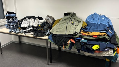 Kleidung und Schuhe liegen gestapelt auf einem Tisch