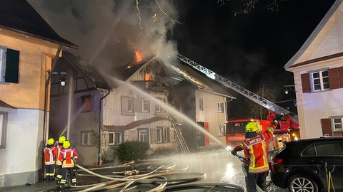 Feuerwehrleute löschen ein brennends Haus.