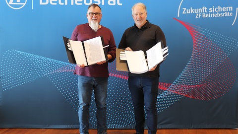 Gesamtbetriebsratsvorsitzender Achim Dietrich (rechts) und sein Stellvertreter Mario Kläs präsentieren zwei dicke Leitz-Ordner, in denen die Vorschläge der ZF-Beschäftigten abgelegt sind. Der Gesamtbetriebsrat ist überzeugt, dass darin ein Millionenpotenzial steckt, um die wirtschaftliche Situation von ZF zu verbessern.