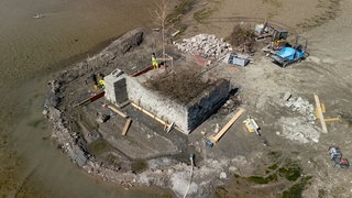 Bauarbeiter sanieren eine alte Mauer um die Insel Hoy. Hoy ist mit 53 Quadratmetern die kleinste Insel im Bodensee und normalerweise vom Wasser umspült. Wegen des aktuell sehr niedrigen Wasserstands können Baumaschinen trocken bis dorthin fahren. 