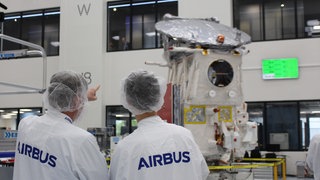 Zwei Airbus-Mitarbeiter vor dem Satellit EarthCare