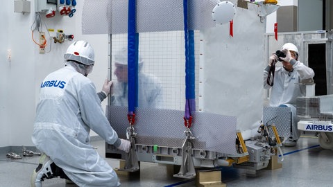 Ingenieure verladen die Atomuhr in einem Frachtraum.