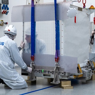 Ingenieure verladen die Atomuhr in einem Frachtraum.