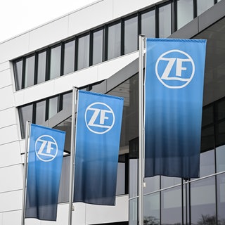 Drei Fahnen mit dem Logo der ZF Friedrichshafen AG wehen vor der Verwaltungszentrale des Konzerns. ZF verkürzt in Friedrichshafen die Arbeitszeit von 2.800 Mitarbeitern.