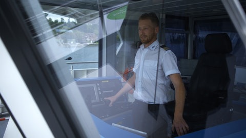 Ein Mann steht am Steuer eines vollektrisch angetriebenen Passagierschiffes. Die E-Fähre ist ein Beispiel für nachhaltigen Schiffsverkehr auf dem Bodensee.