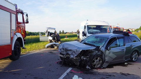 Mehrere Autos stehen nach einem schweren Unfall beschädigt auf der Straße.