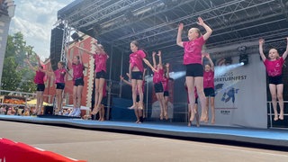 Tanzgruppe in pinken T-Shrits und schwarzen Hosen auf einer Bühne