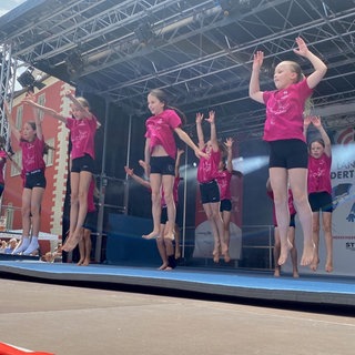 Tanzgruppe in pinken T-Shrits und schwarzen Hosen auf einer Bühne