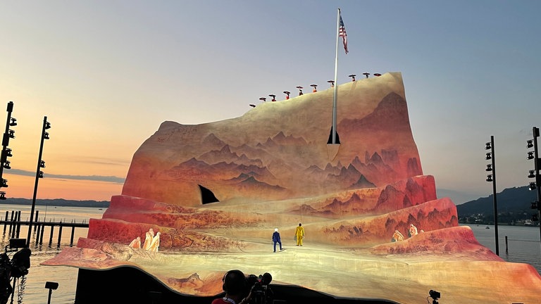 Wie in Abendsonne getaucht wirkt das Bühnenbild. Aus dem Blatt Papier ragt ein Fahnenmast mit der amerikanischen Flagge bei Madame Butterfly bei den Bregenzer Festspielen 2022